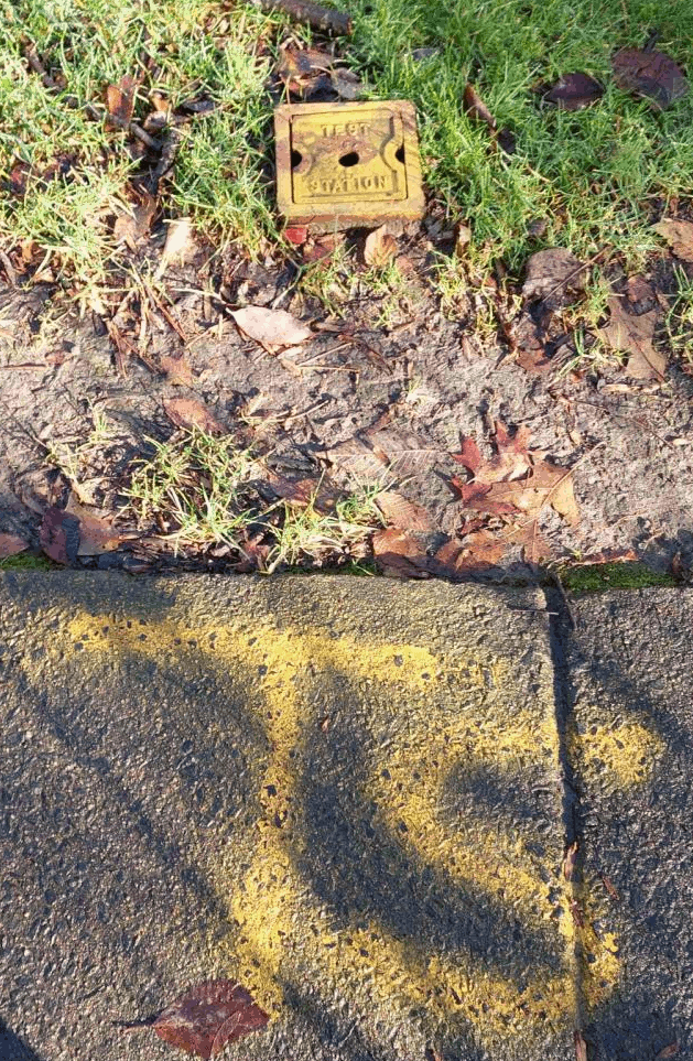 A yellow spraypainted 'TS' pointing to a metal cover including the text 'Test Station'.